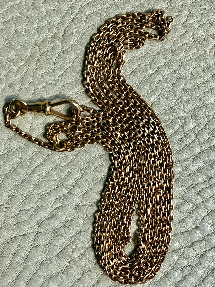 Gold chain necklace on a textured light gray surface. Penelope Penelope vintage 18k gold fine jewelry