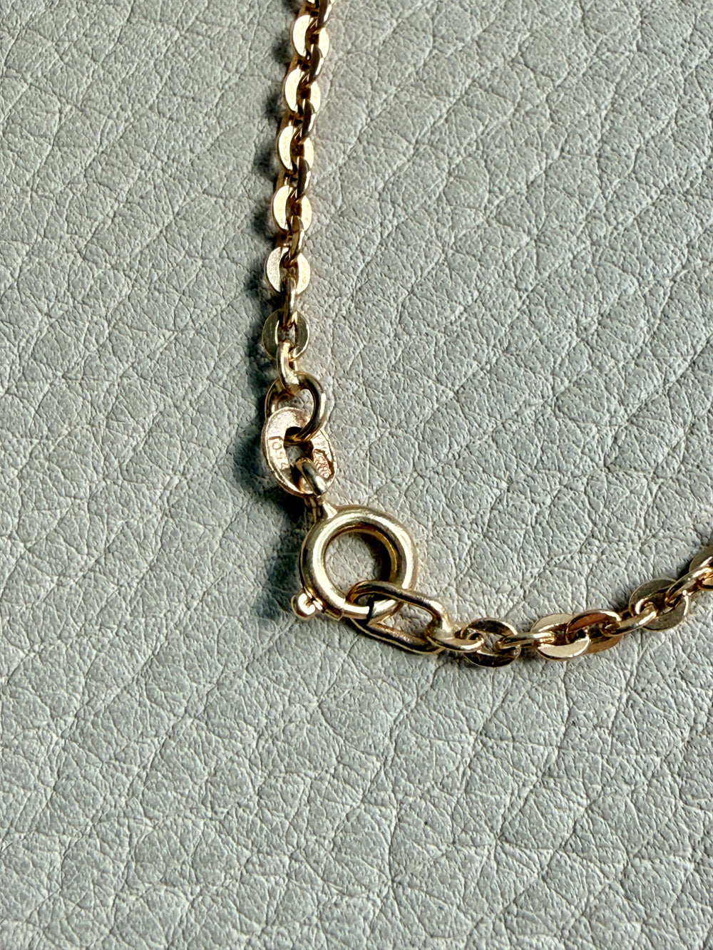 Gold chain necklace on a light gray textured background