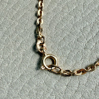 Gold chain necklace on a light gray textured background