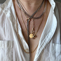 Close-up of layered necklaces on a person wearing a white shirt.