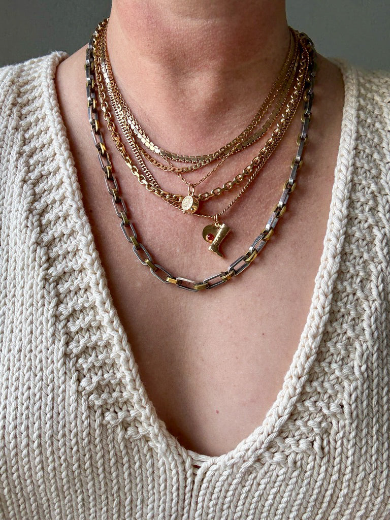 Necklace with gold and silver chains on a person wearing a beige sweater.