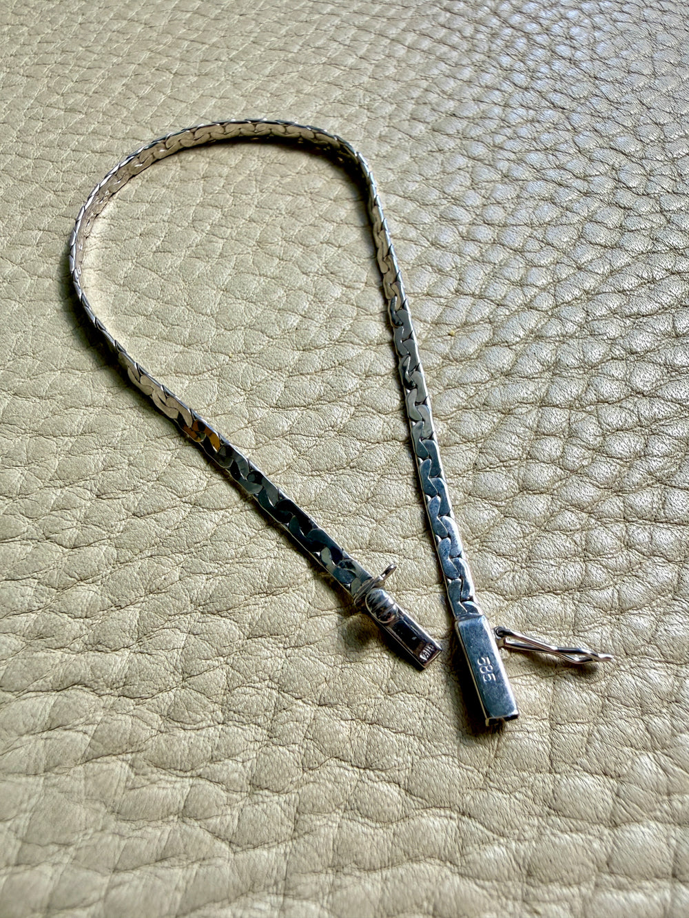 14k white gold bracelet on a textured beige surface