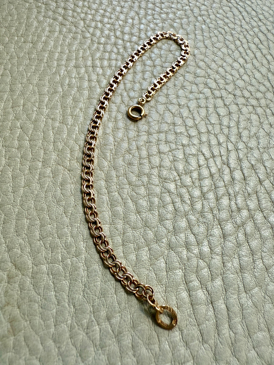 Gold chain bracelet on a textured light green surface