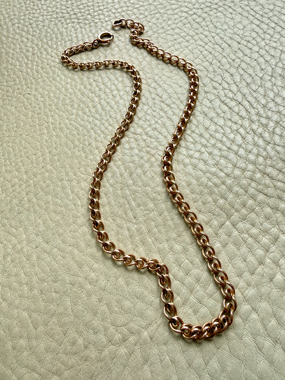 18k vintage yellow gold chain necklace on a textured light green surface