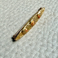 Gold antique brooch with decorative elements on a textured light gray background