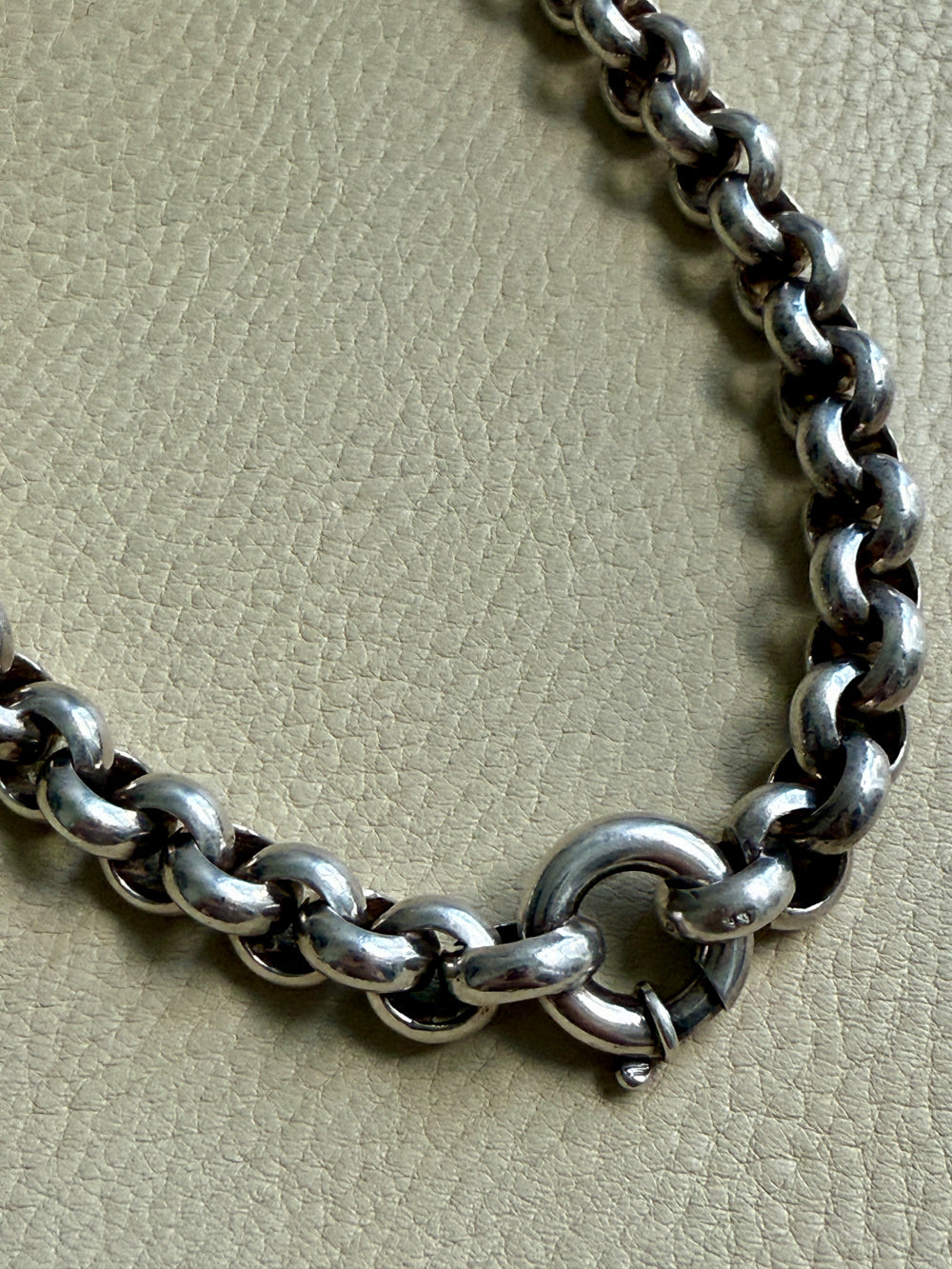Silver chain bracelet on a textured beige surface