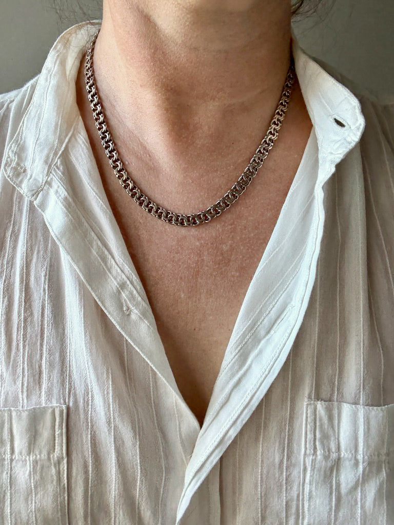 Person wearing a white shirt with a chain necklace