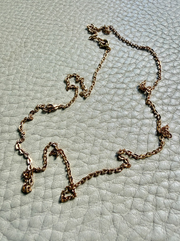 Gold chain necklace on a textured light blue surface