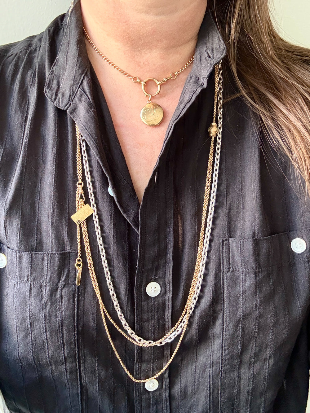 Person wearing multiple gold necklaces with a dark shirt