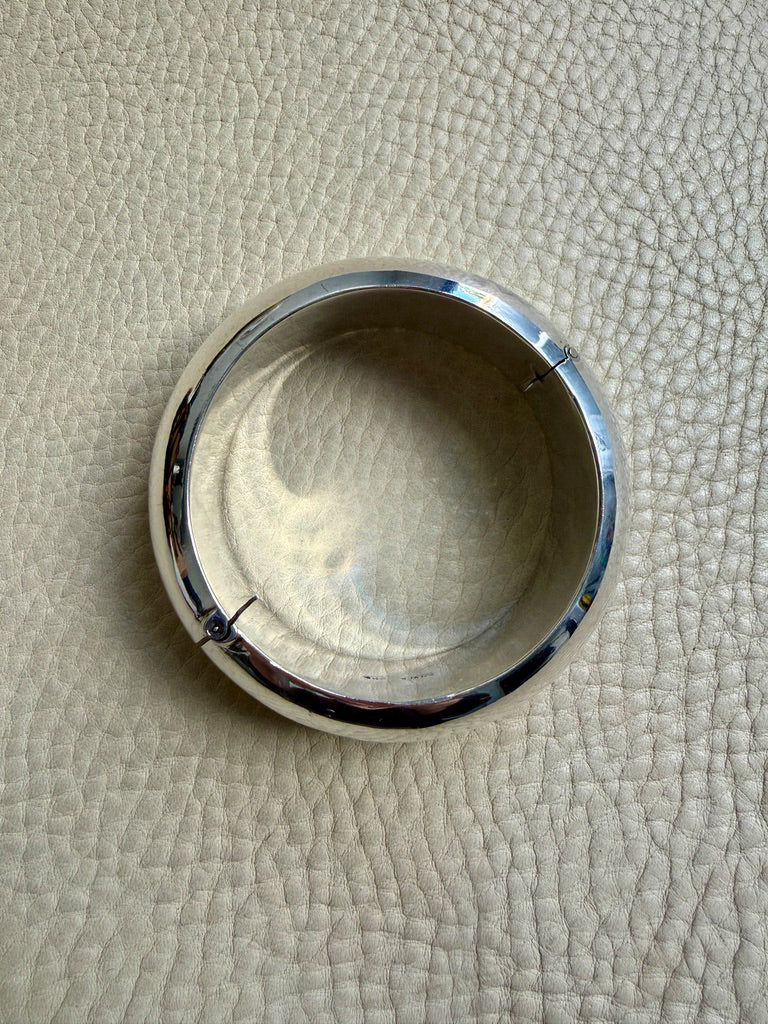 Silver bangle bracelet on a textured beige surface