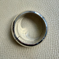 Silver bangle bracelet on a textured beige surface