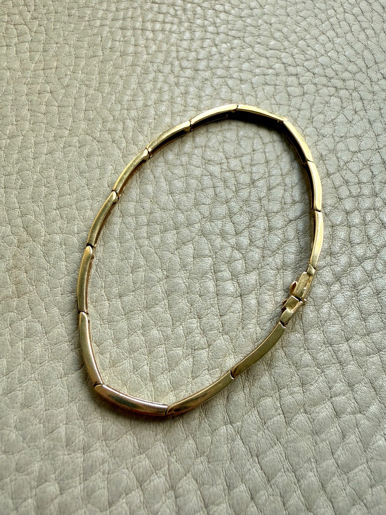 Gold bracelet on a textured beige surface