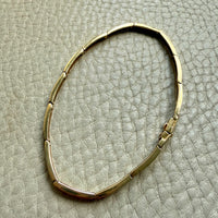 Gold bracelet on a textured beige surface