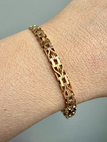 Gold bracelet on a wrist with a neutral background. Penelope Penelope Vintage Jewelry