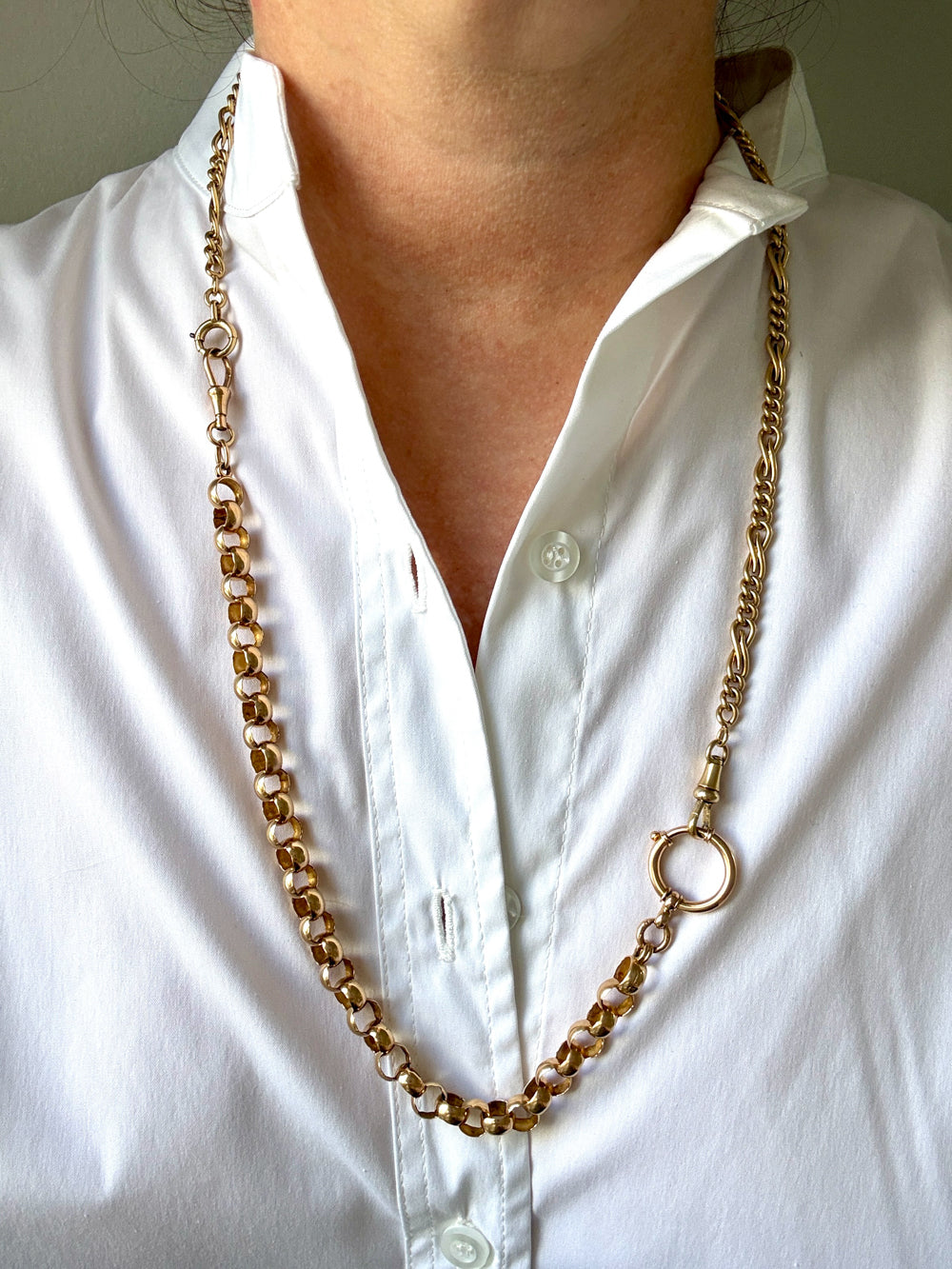 An antique 18k gold watch chain necklace with a large bolt clasp, worn around the neck of a person wearing a white button-down shirt. penelopepenelope.com