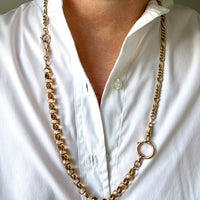 An antique 18k gold watch chain necklace with a large bolt clasp, worn around the neck of a person wearing a white button-down shirt. penelopepenelope.com