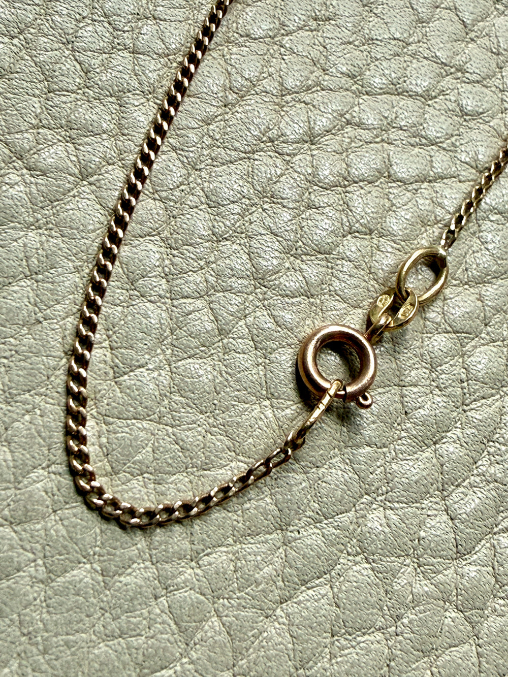Gold chain necklace with clasp on a textured light gray background