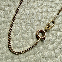 Gold chain necklace with clasp on a textured light gray background