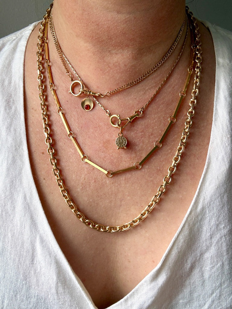 Close-up of a person wearing multiple gold necklaces on a white background