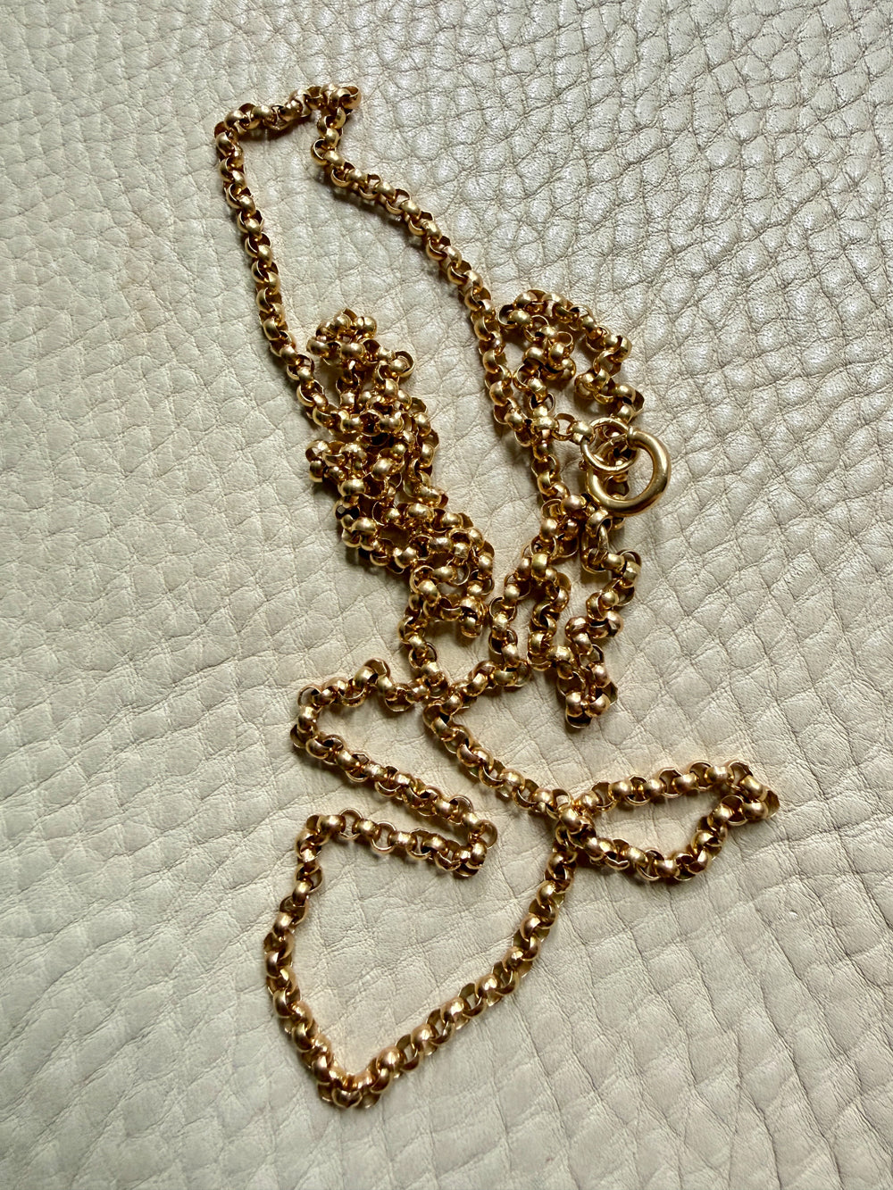 18k Gold antique rolo link necklace on a textured light gray surface