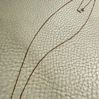 vintage 18k gold chain necklace on a textured light gray surface