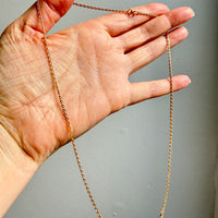 Hand holding a gold chain against a gray background