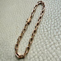 18k Gold chain bracelet on a textured light gray surface