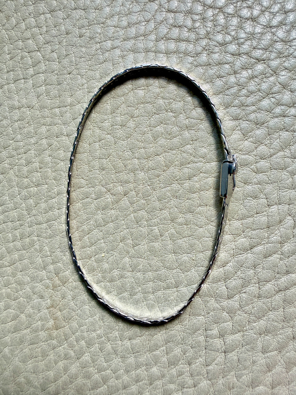 14k white gold bracelet on a textured beige surface