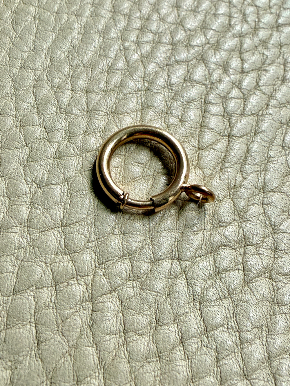 large gold bolt clasp on a textured beige surface PenelopePenelope.com 