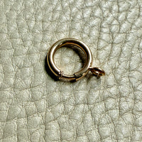 large gold bolt clasp on a textured beige surface PenelopePenelope.com 