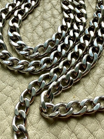 Close-up of a vintage 14k white gold chain on a textured beige surface