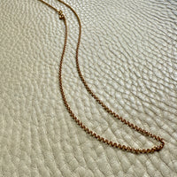 Gold chain necklace on a textured beige surface
