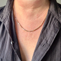 Person wearing a gold necklace with a plain background