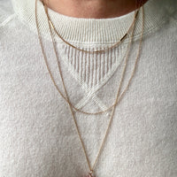 Necklaces with a red pendant worn by a person on a light gray background