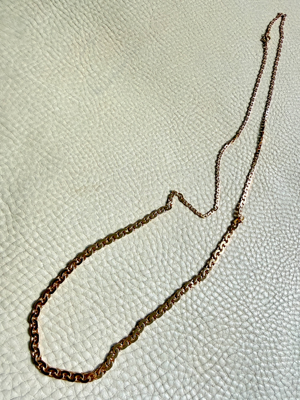 18k gold antique chain necklace on a textured light gray background