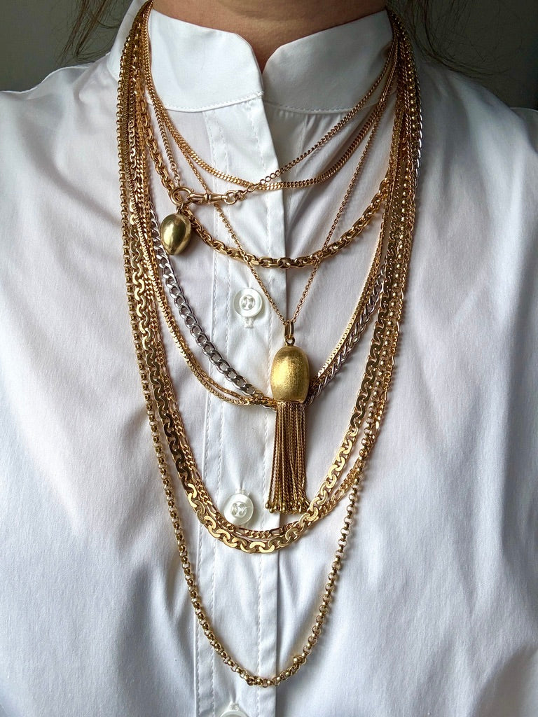 Multiple gold necklaces on a white shirt