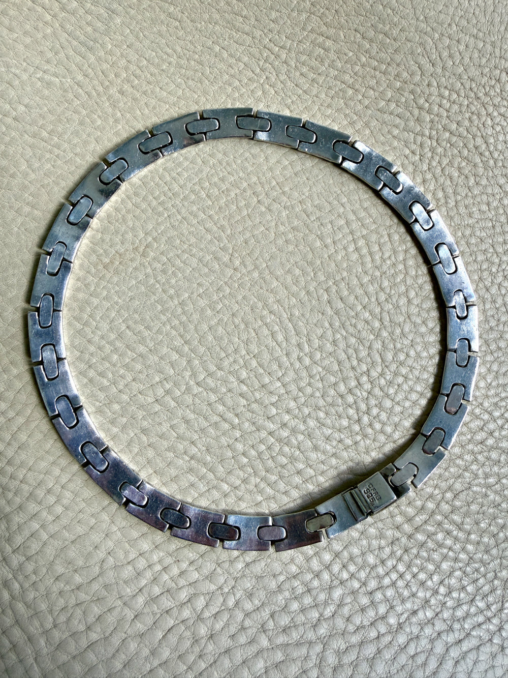 vintage silver necklace on a textured beige surface