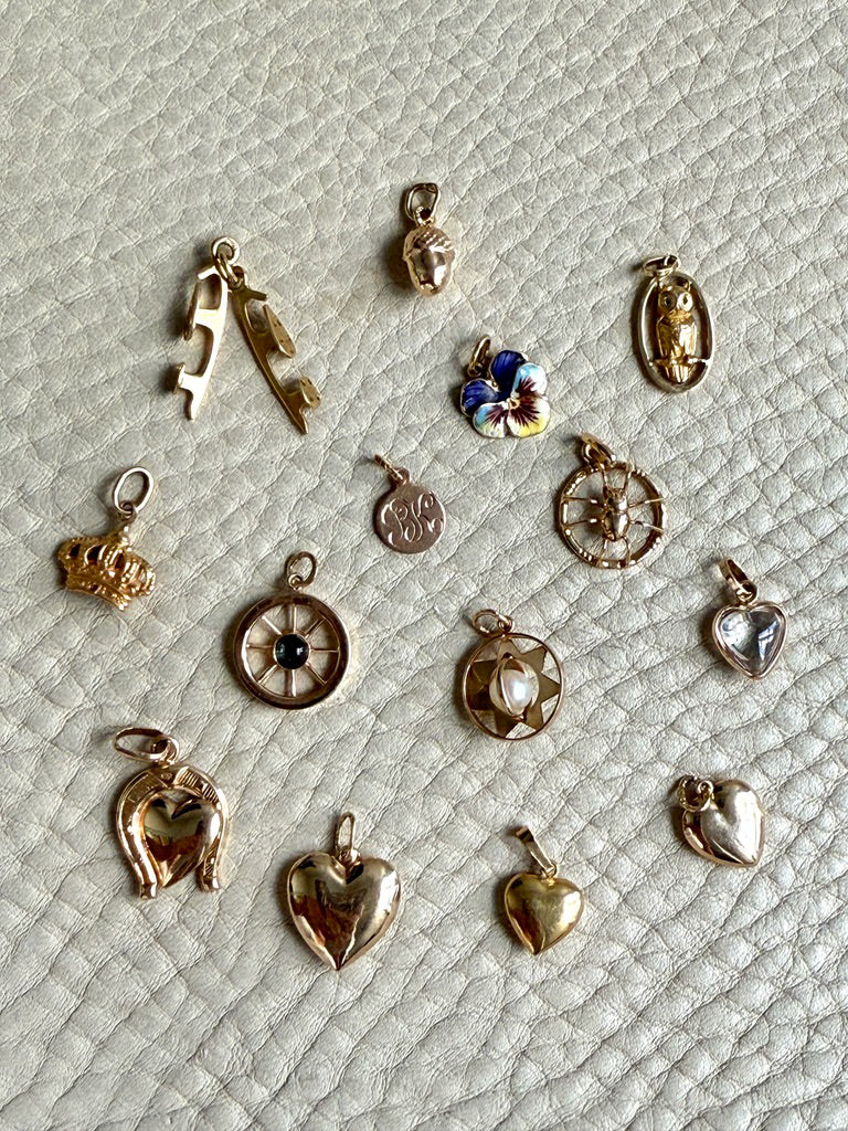 Collection of various small gold charms on a textured light gray surface