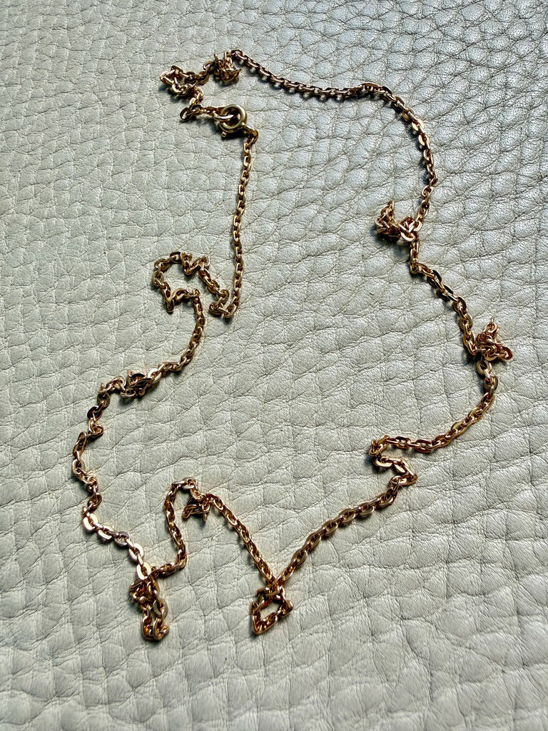 antique 18k gold chain necklace on a textured light gray surface