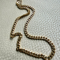 18k Gold chain necklace on a textured light gray surface