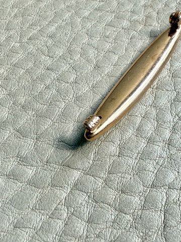 Gold brooch  on a textured light gray surface