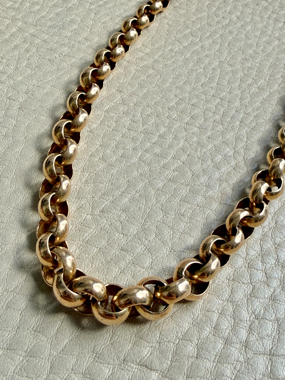 Gold chain necklace on a textured light gray background