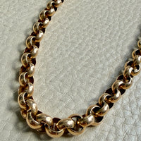 Gold chain necklace on a textured light gray background
