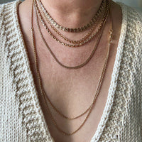 Necklace with multiple chains worn by a person against a neutral background. Penelope Penelope vintage 18k gold fine jewelry