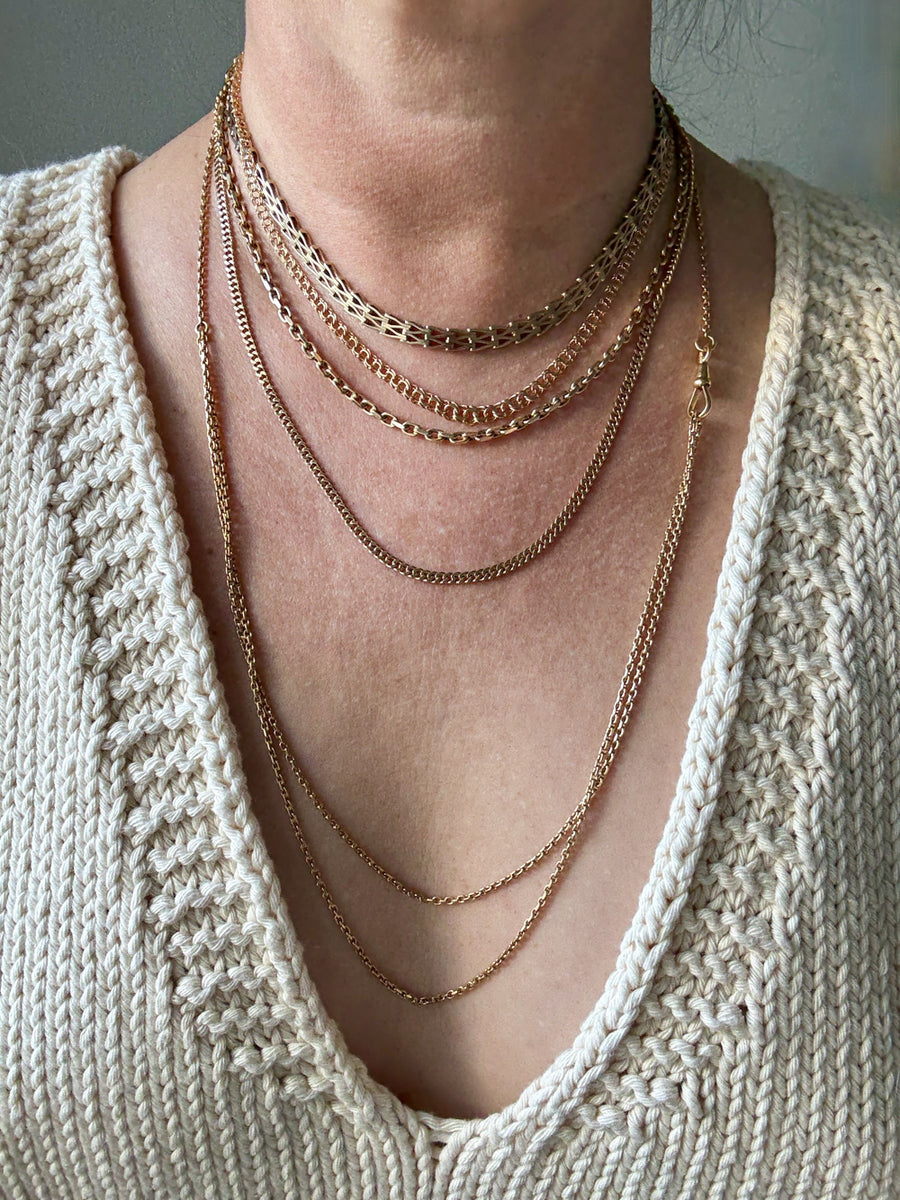 Necklace with multiple chains worn by a person against a neutral background. Penelope Penelope vintage 18k gold fine jewelry