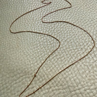 Gold necklace on a textured light gray surface