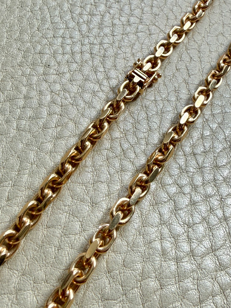 18k Gold chain biker link on a textured light gray background