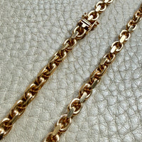 18k Gold chain biker link on a textured light gray background
