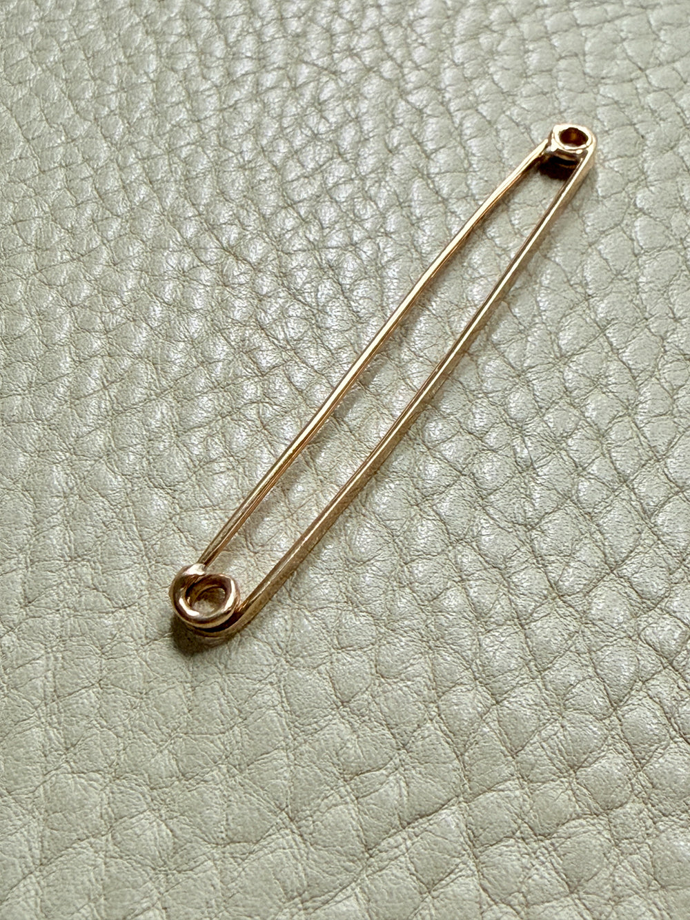 18k Gold antique safety pin brooch on a textured light gray background PenelopePenelope.com
