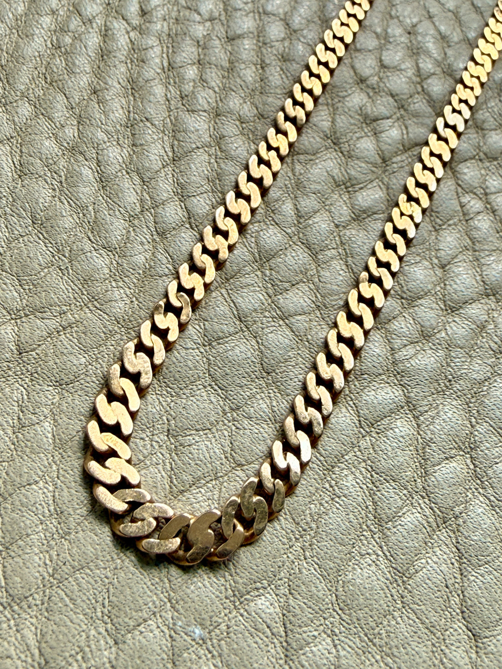 Gold chain necklace on a textured beige surface